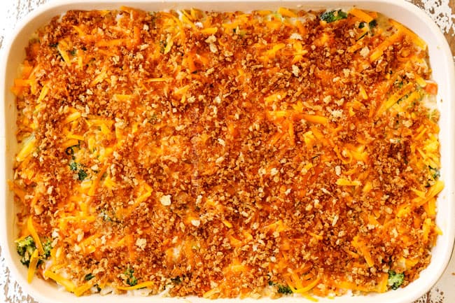 showing how to make chicken broccoli and rice casserole by topping a 9x13 with shredded cheddar followed by panko