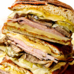 Cuban sandwiches (Cubanos) stacked on top of each other showing the layers of Swiss cheese, ham, mojo pork
