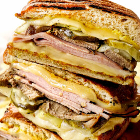 Cuban sandwiches (Cubanos) stacked on top of each other showing the layers of Swiss cheese, ham, mojo pork