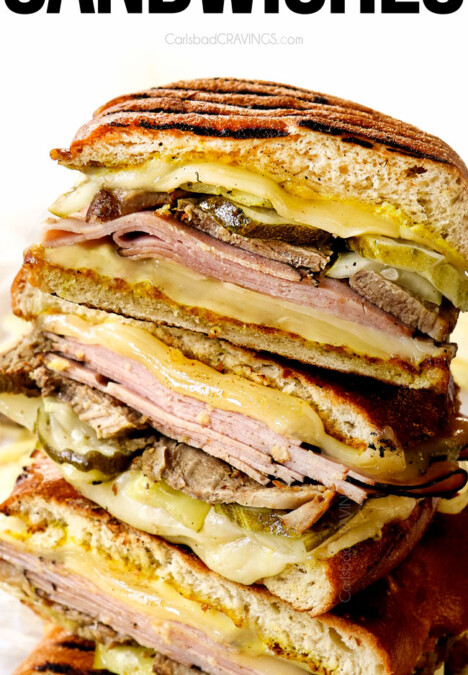 Cuban sandwiches (Cubanos) stacked on top of each other showing the layers of Swiss cheese, ham, mojo pork