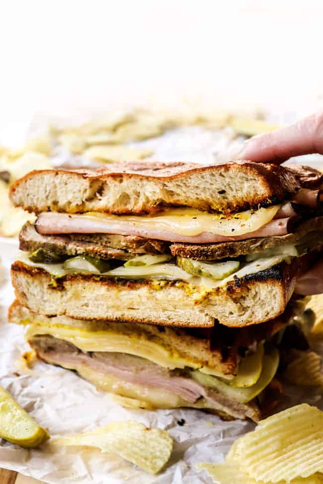 a hand picking up Cubano sandwiches (Cubanos) showing how crispy the bread is