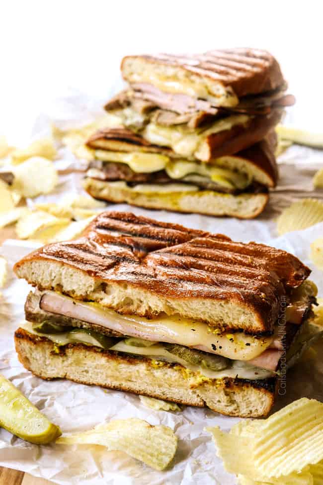 Cubano sandwich (Cubano) on a wood tray surrounded by potato chips showing how crispy the bread is