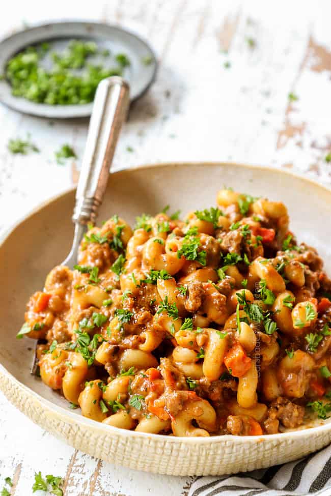 a bowl of homemade hamburger helper in a tan bowl garnished with parsley