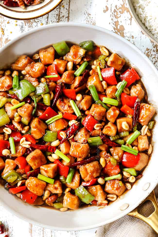 top view of easy kung pao chicken in a white skillet garnished with green onions