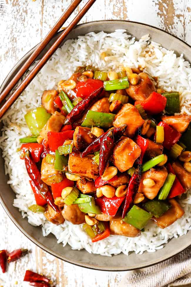 top view showing how to eat kung pao chicken by adding to a bowl of rice, garnishing with green onions and peanuts