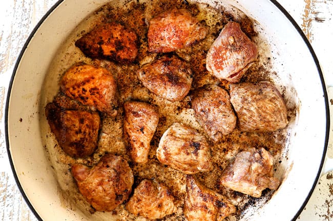 showing how to make pozole by searing chunks of pork in a white Dutch oven