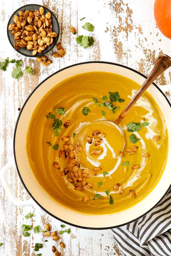 top view of a ladle scooping up creamy pumpkin soup recipe garnished with cilantro
