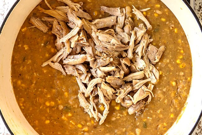 showing how to make white bean chicken chili by adding shredded chicken back to the thickened soup