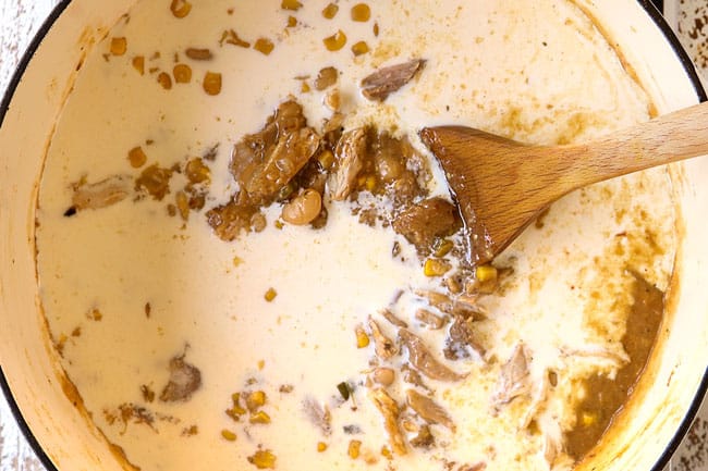 showing how to make creamy white bean chicken chili by adding half and half to the soup pot