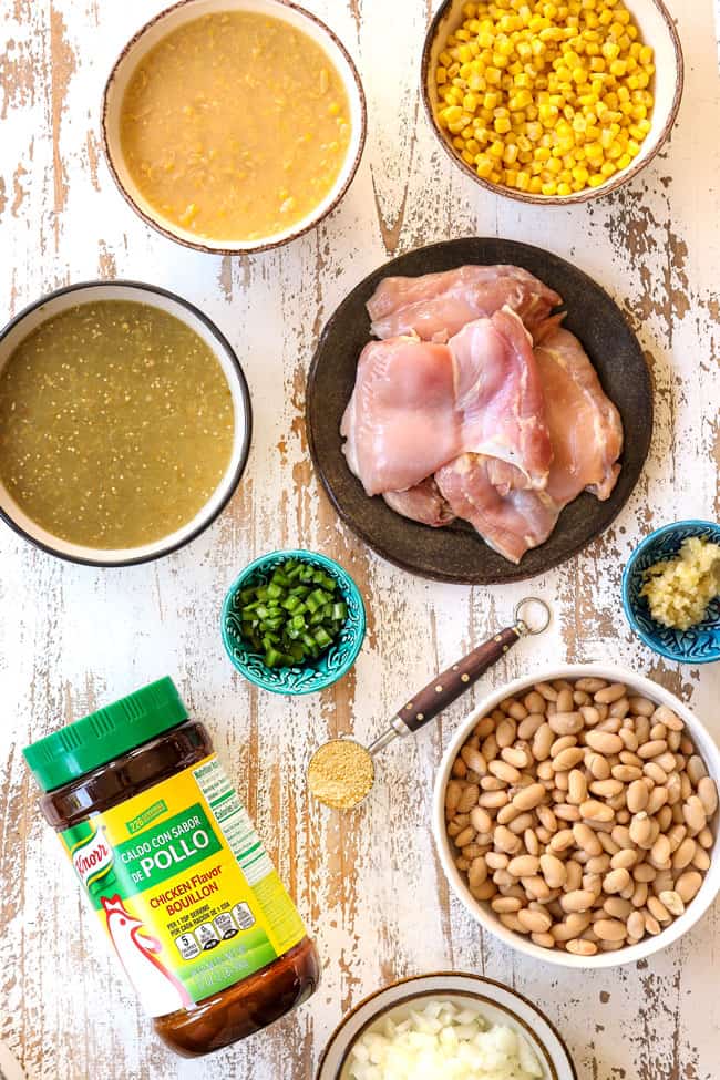 showing how to make best white chicken chili recipe with a top view of ingredients:  corn, creamed corn, salsa verde, chicken thighs, jalapenos, garlic, white beans and onions