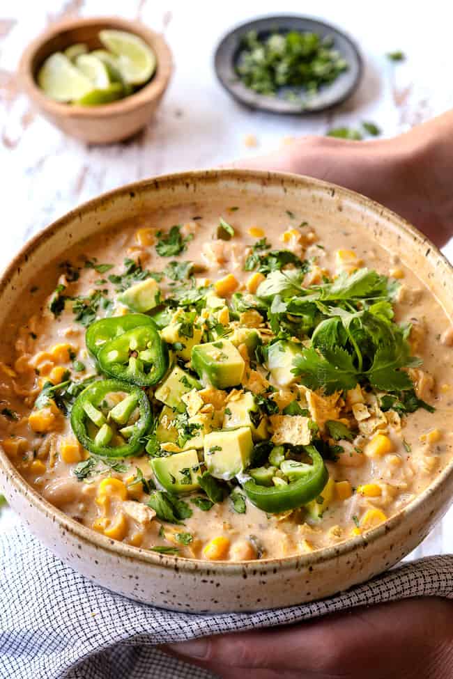 two hands holding a bowl of best white chicken chili  recipe