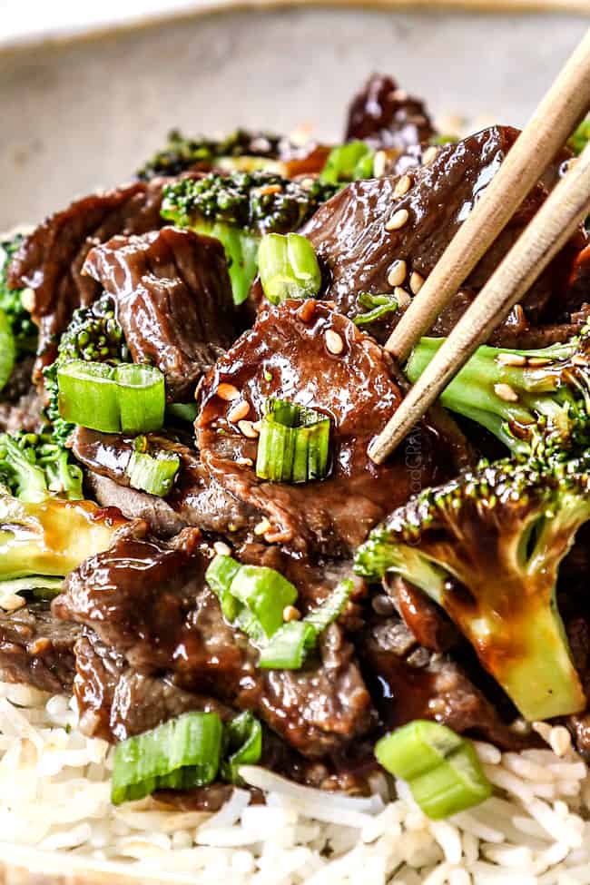 showing how to eat slow cooker crockpot beef and broccoli recipe by picking up a slice of beef with chopsticks