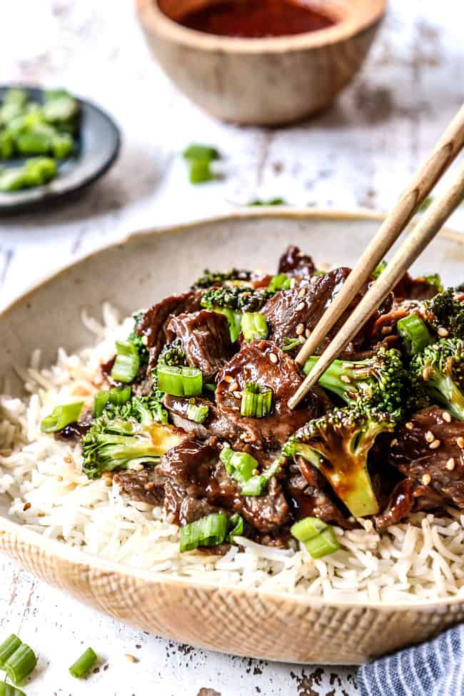 showing how to eat crockpot beef and broccoli by picking beef up with chopsticks served over rice