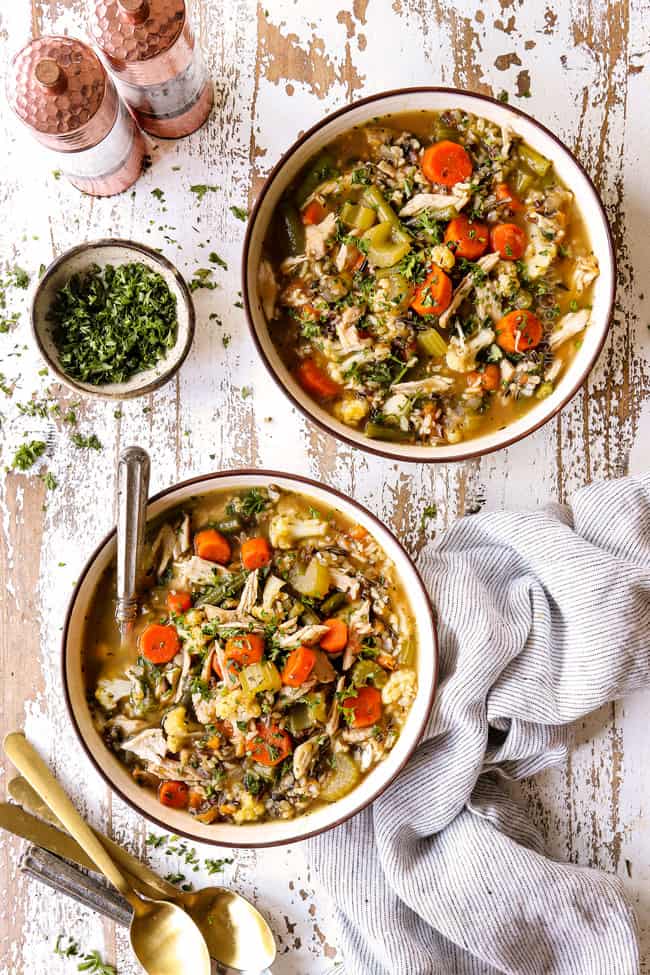top view of two bowls of leftover turkey soup with rice, carrots, celery, onions and garlic