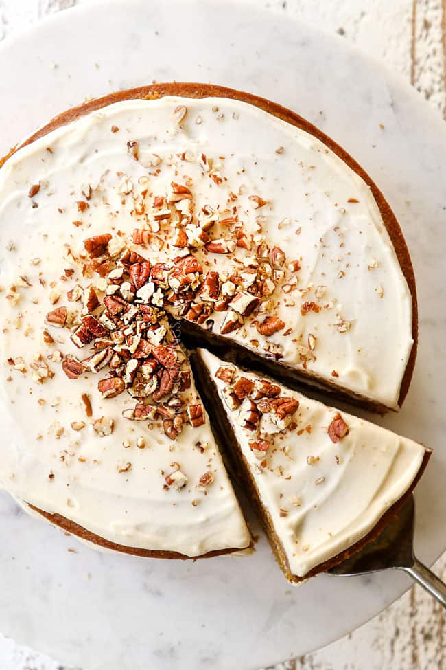 showing how to make pumpkin spice cake by garnishing the top with chopped pecans