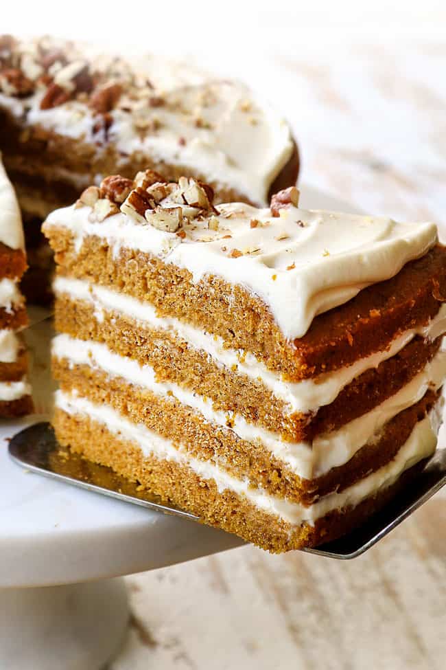up close of a slice of pumpkin spice cake on cake server being pulled away from the cake stand
