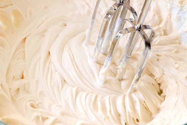 showing how to make pumpkin spice cake by whipping cream cheese, sugar and maple together until light and fluffy