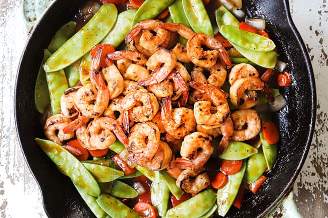 showing how to make shrimp stir fry recipe by adding shrimp to stir fry and combining