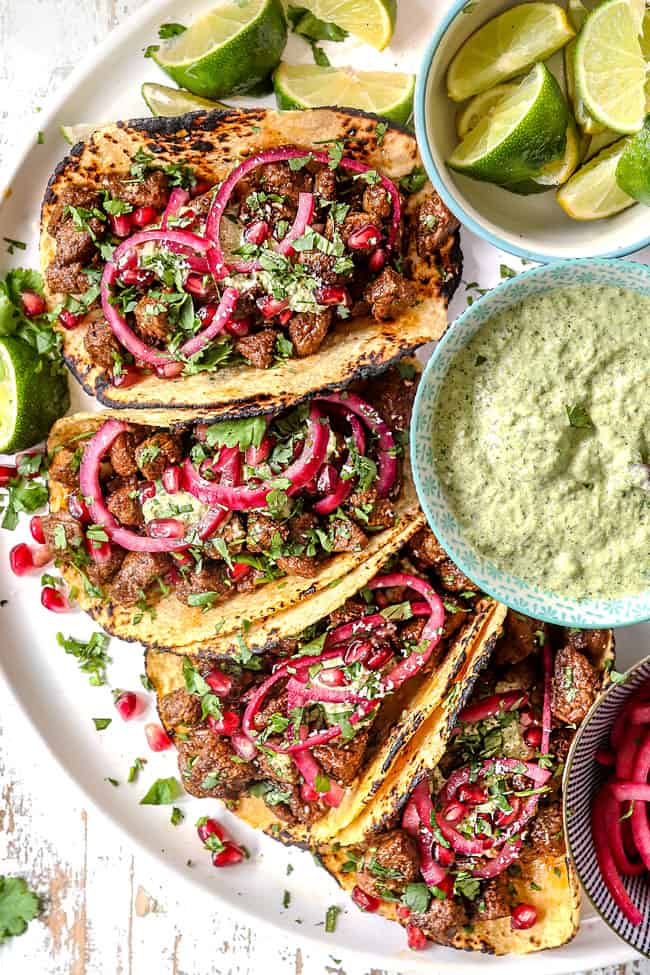 top view of steak taco recipe lined on a white plater, cooked with steak seasonings and garnished with cilantro