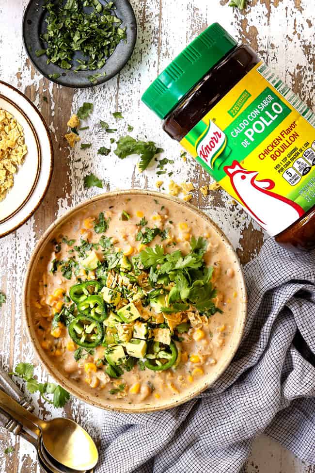 top view of creamy white chicken chili in a bowl with  avocados, cilantro and jalapenos
