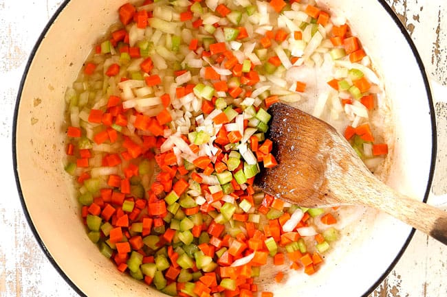 showing how to make Chicken Parmesan Pasta by sauteeing onions, carrots and celery in a large white pot