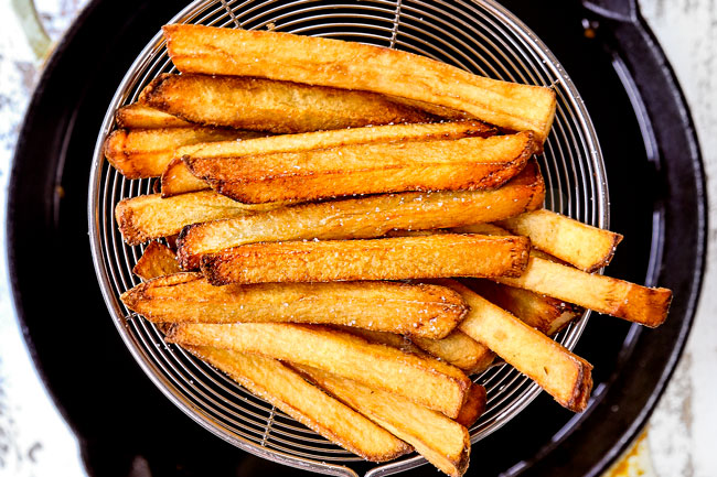 showing how to make poutine recipe by frying the potatoes for the second fry until golden and crispy