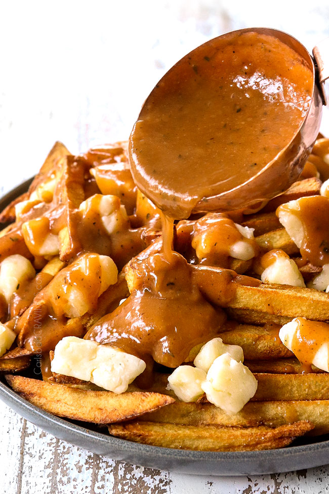 showing how to make poutine by drizzling with gravy with a ladle