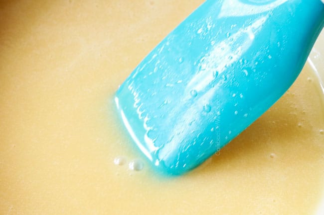 showing how to make red velvet cheesecake by melting white chocolate in a saucepan until smooth