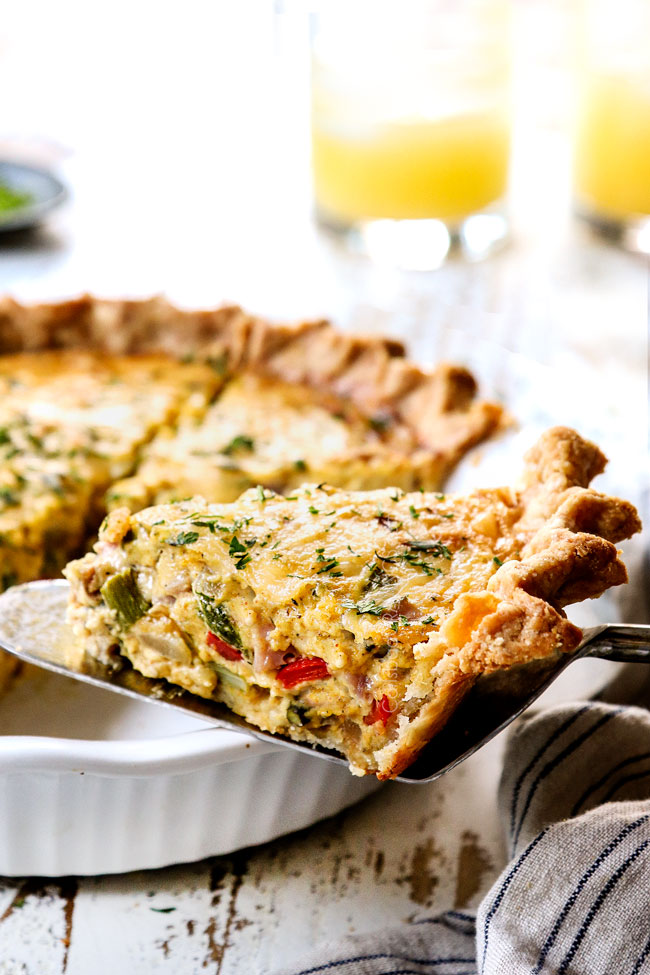 showing how moist ham and quiche recipe is by holding up a slice