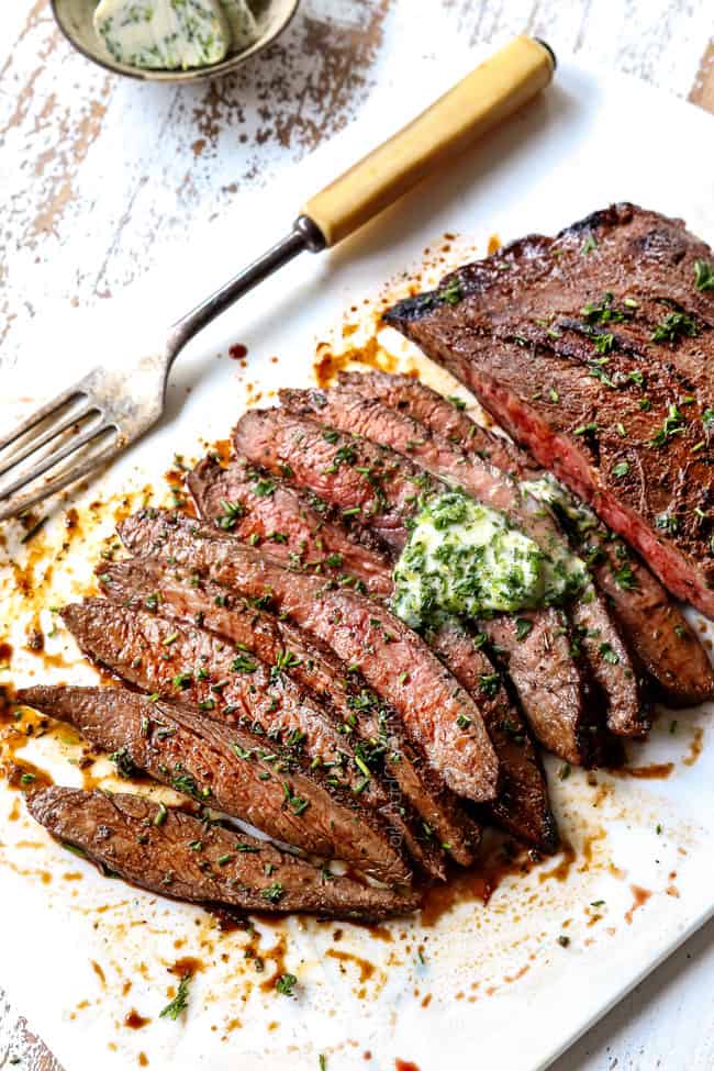 London Broil recipe on a white cutting board with herb butter