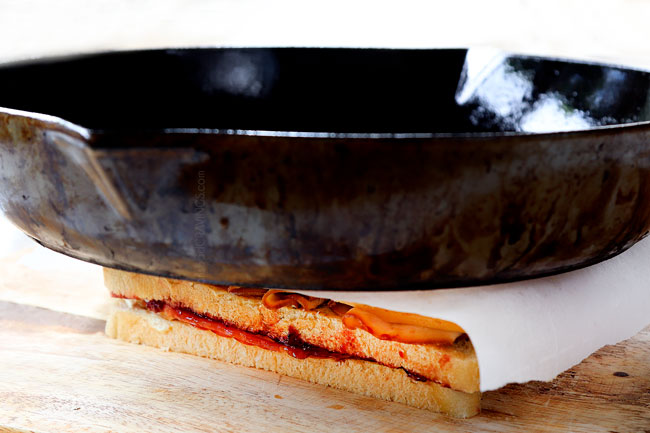 showing how to make Monte Cristo sandwich recipe by pressing the sandwich with a cast iron skillet