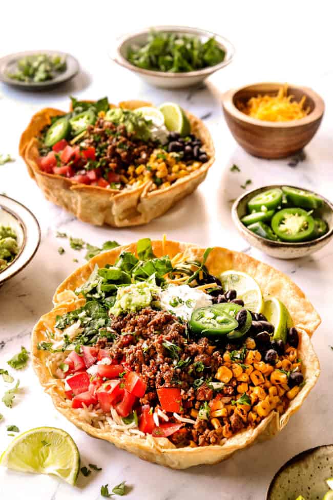 taco bowl recipe in taco bowl shells with ground beef, corn, black beans, tomatoes, lettuce and sour cream and guacamole