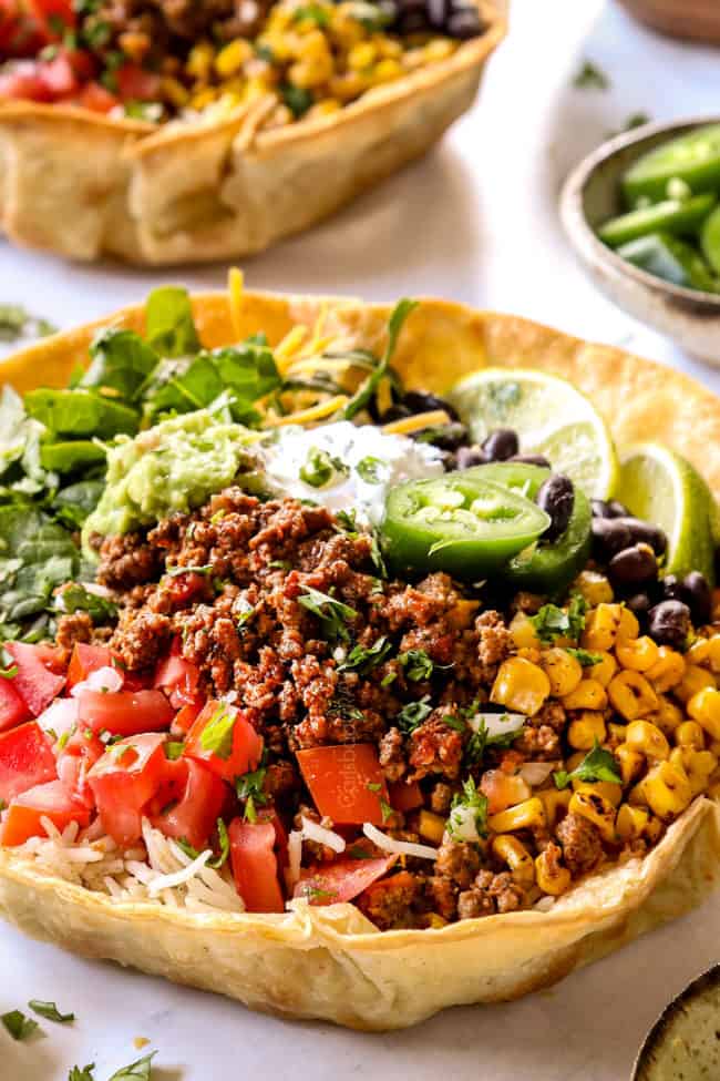 up close of taco bowl recipe with taco bowl shells filled with ground beef, corn, tomatoes and black beans
