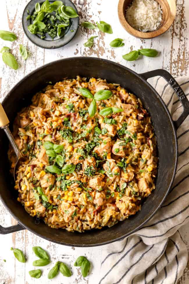 top view of basil chicken in Dutch oven surrounded by fresh basil