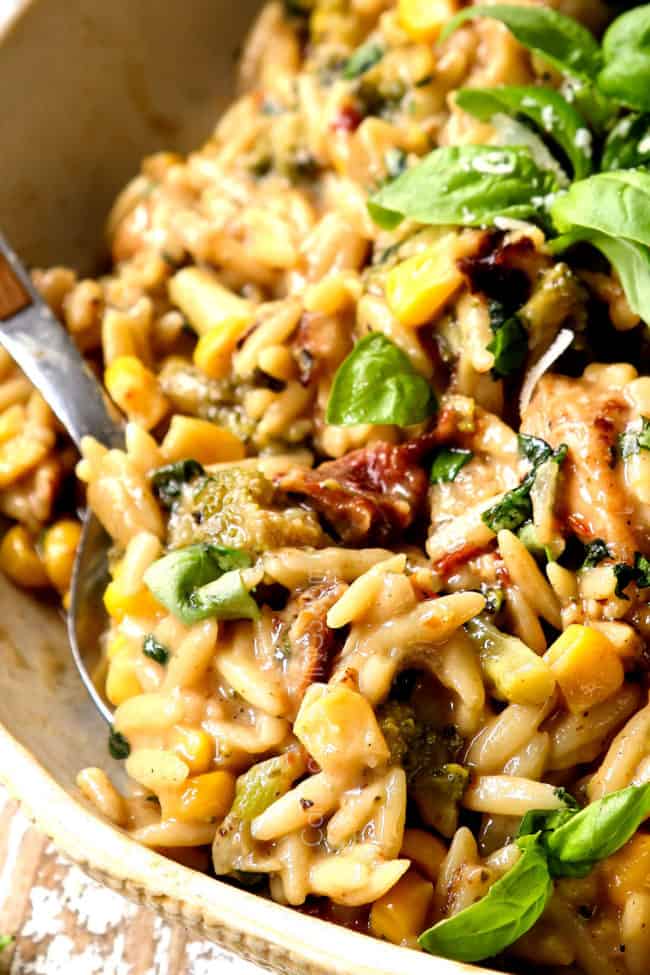 a spoon scooping up basil chicken with fresh basil