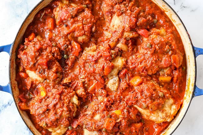 showing how to make chicken cacciatore recipe by adding chicken back to the pot and covering with sauce