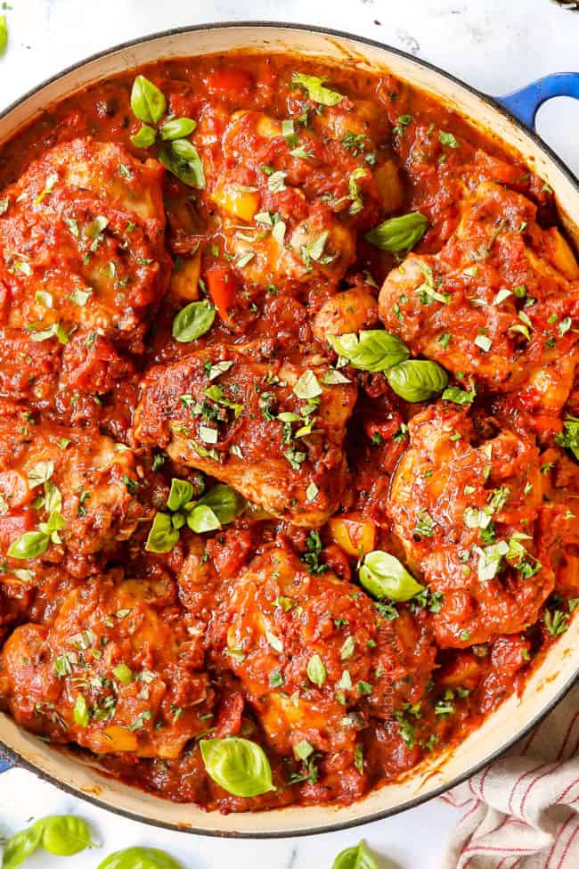 top view of chicken cacciatore recipe in a blue braiser with a serving spoon