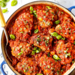 top view of chicken cacciatore recipe in a blue braiser with a serving spoon