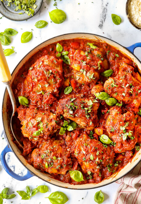 top view of chicken cacciatore recipe in a blue braiser with a serving spoon