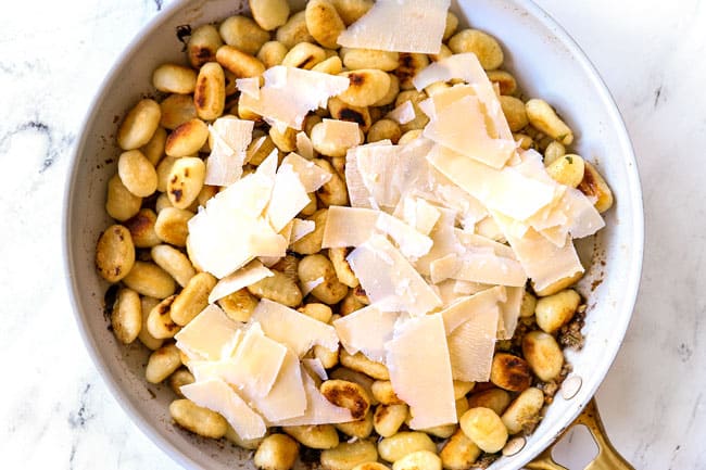 showing how to make gnocchi recipe by tossing gnocchi in sauce and adding shaved Parmesan