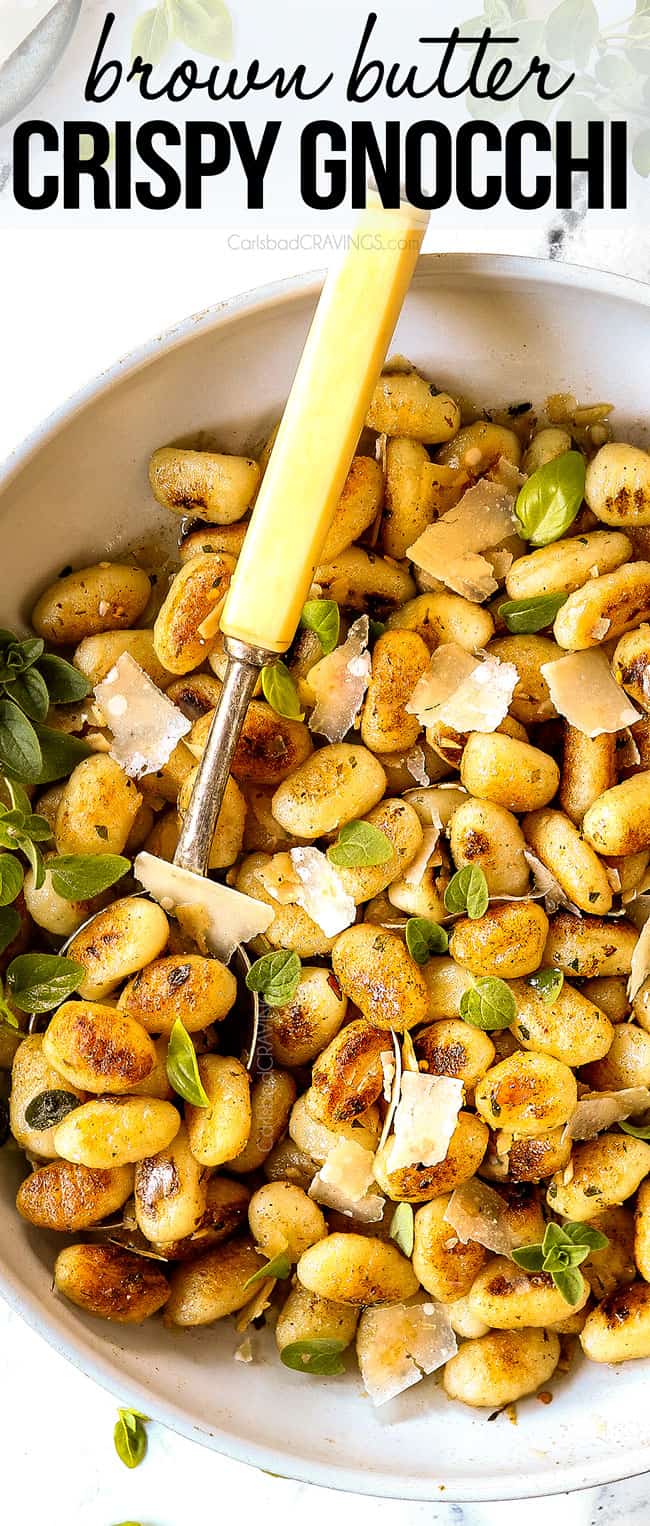top view of gnocchi in a white skillet garnished with shaved Parmesan