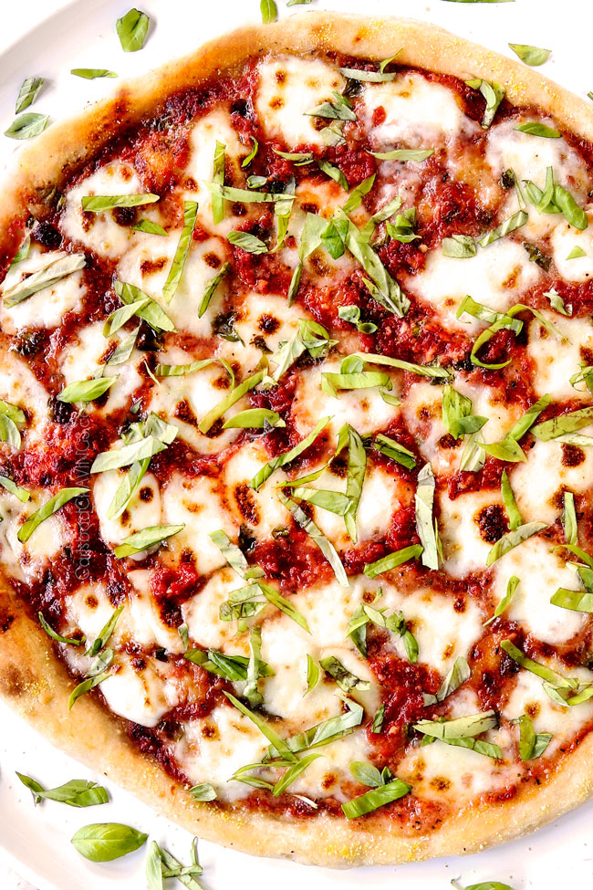 showing how to make margherita pizza recipe by topping with fresh basil