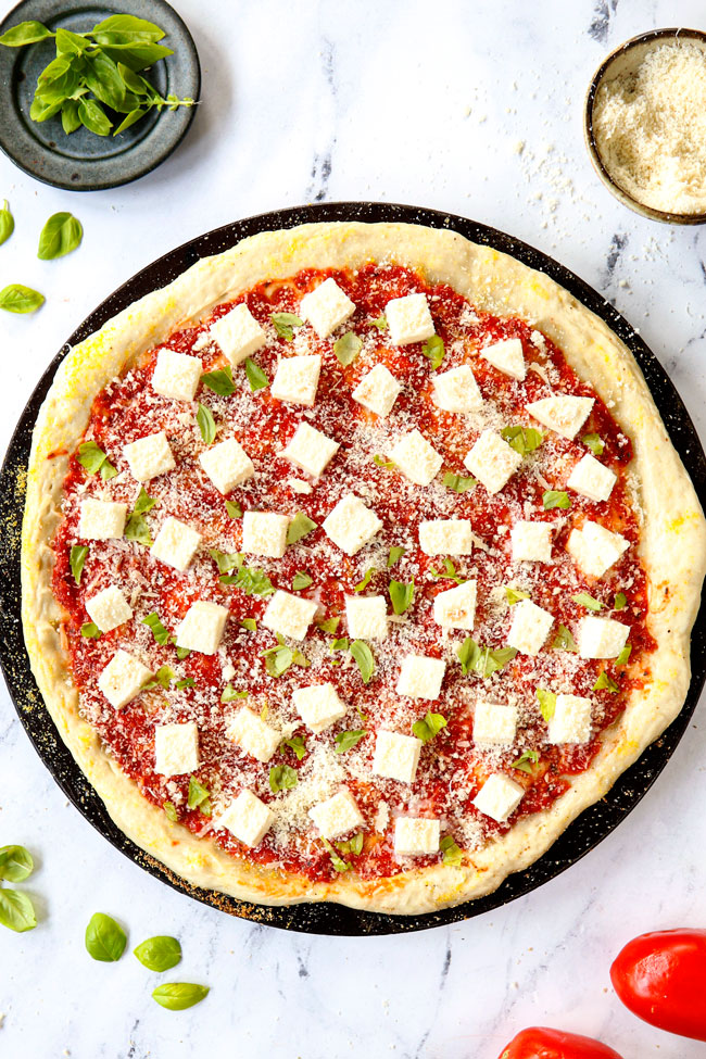 showing how to make margherita pizza recipe by adding sauce, mozzarella and basil