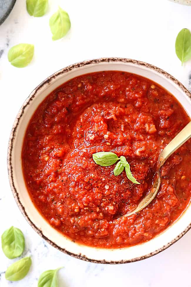 top view of homemade pizza sauce recipe with a gold spoon with basil on top