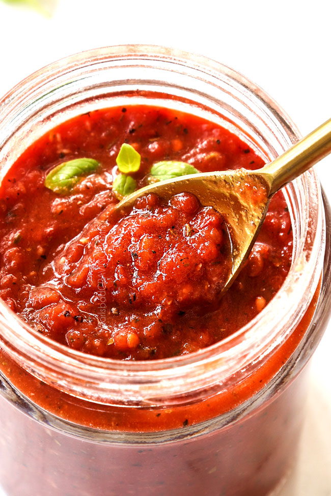 showing consistency of margherita pizza sauce by scooping up sauce with a spoon