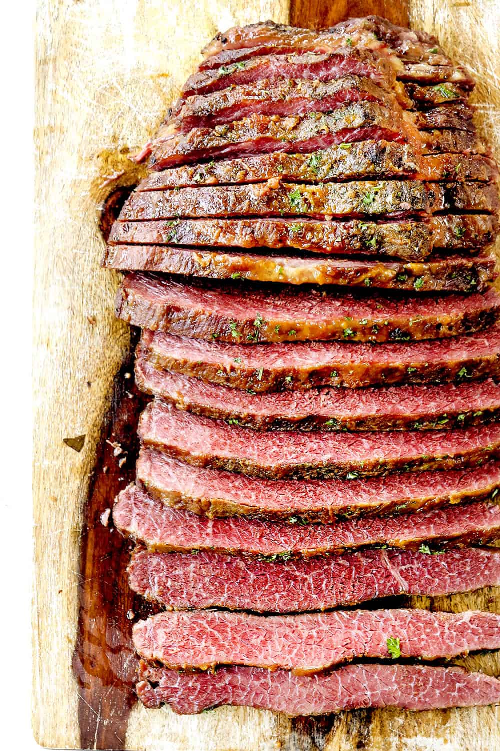 showing how to make corned beef recipe by slicing corned beef brisket across the grain on a wood cutting board