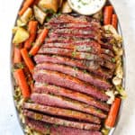 top view of corned beef and cabbage on a platter with potatoes, carrots and horseradish sauce