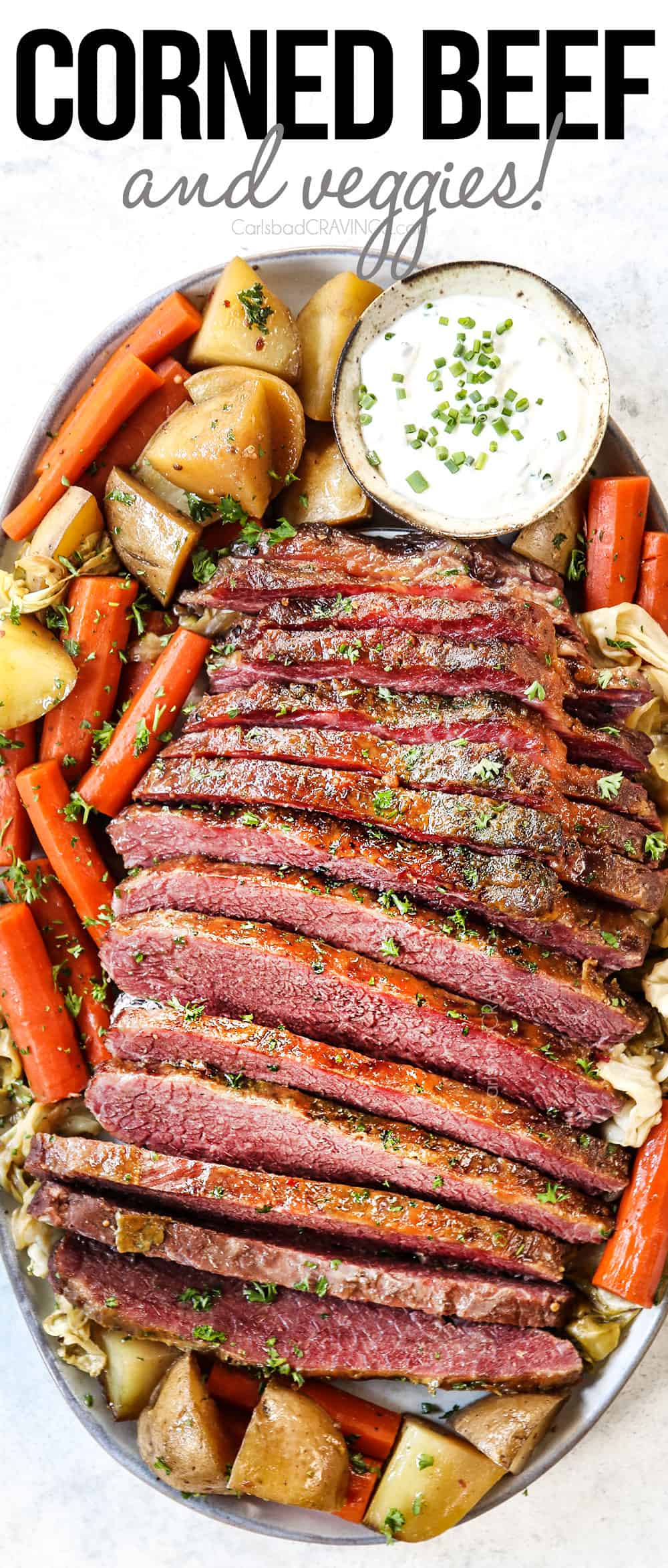top view of corned beef and cabbage on a platter with potatoes, carrots and horseradish sauce