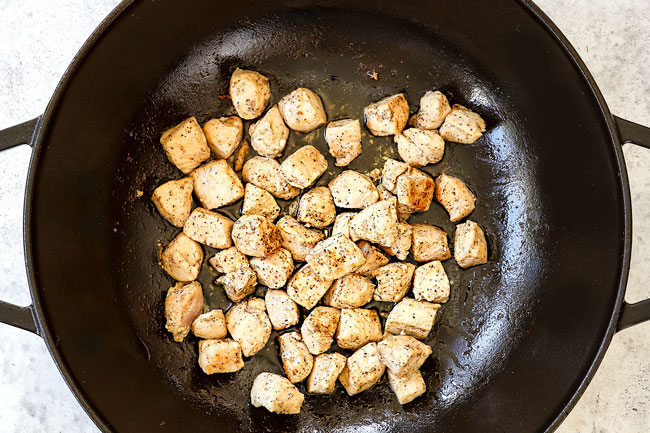 showing how to make chicken pesto pasta recipe by sauteing chicken in a black Dutch oven