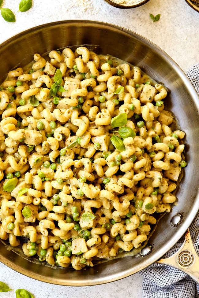 showing how to make chicken pesto pasta by garnishing with Parmesan